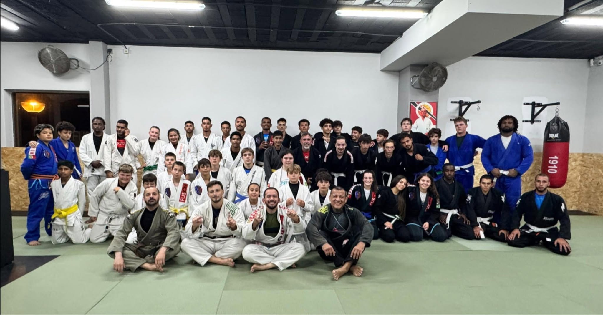 Turma de Jiu-Jitsu da Fusion Studio reunida no tatame com kimonos de várias faixas